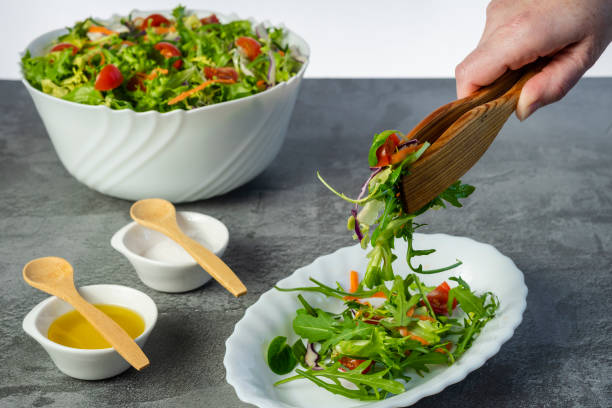 istock Woman's hand serving green and healthy salad plate 1302614656