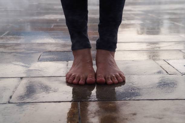Woman feet without shoes on the street with wet floor The freedom of a woman walking barefoot down the street after a little rain Barefoot stock pictures, royalty-free photos & images