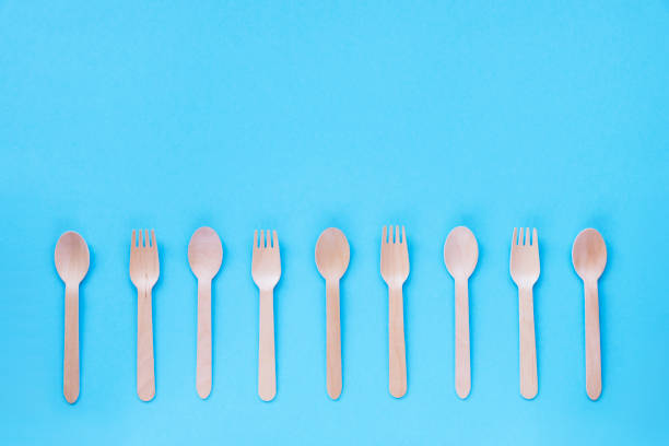 istock Disposable bamboo spoons and forks on blue background. Zero waste concept. Top view, flat lay, copy space 1302616071