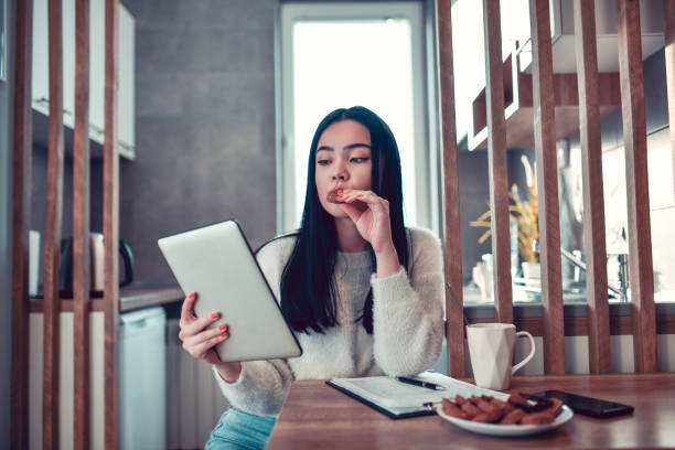 istock Female Beauty Exploring Social Media On Digital Tablet While Eating Cookies With Coffee 1302616263