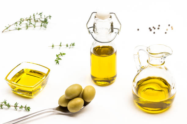 olives vertes dans la cuillère en métal. huile d’olive dans le bocal en verre - vinegar bottle herb white photos et images de collection