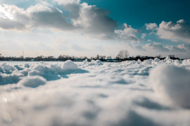 Winter landscape with snow covered field on the background of blue sky and clouds.
