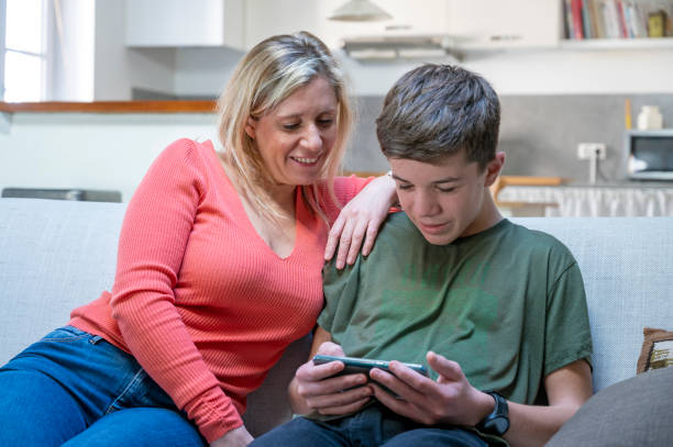 istock teenager sharing content on cell phone with mom at home 1302617331