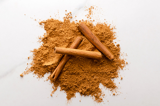 Closeup of dried raw cinnamon sticks on the powder as a background