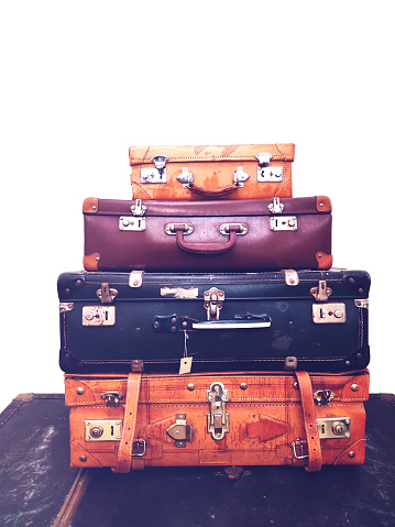 Close up stack of four old vintage antique grunge travel luggage brown leather suitcase with vintage sign. Travel luggage concept. Retro style filtered photo