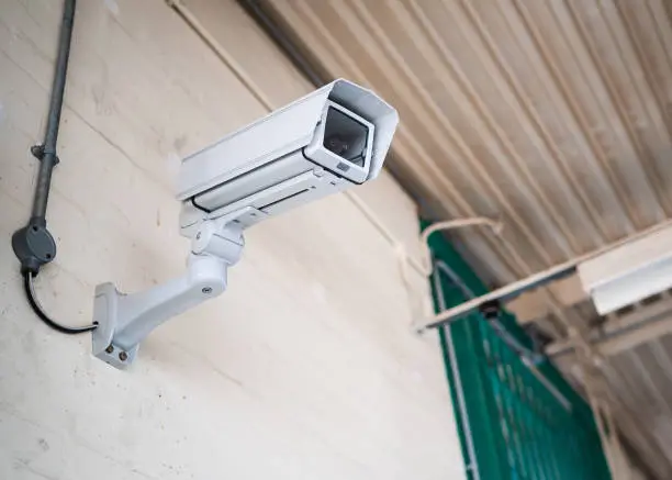 Prison communal room jail in sunlight of high security run down immigration detention centre in England with professional CCTV security camera monitoring the room activity