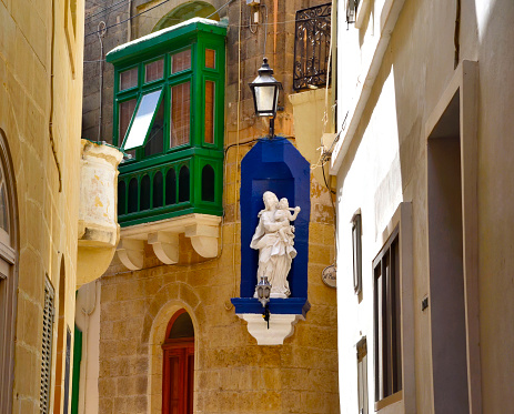 Wooden balcony in center of La Valletta and the statue of Virgin Mary. Malta
