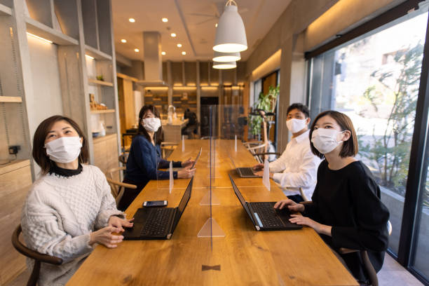 istock Freelance workers with protective face mask having meeting at office, using plastic patition 1302622133