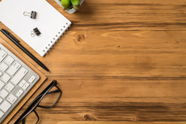 istock Overhead above flat lay view photo of computer keyboard flowerpot clear spiral notebook eyeglasses isolated light brown backdrop with place for text 1302622143