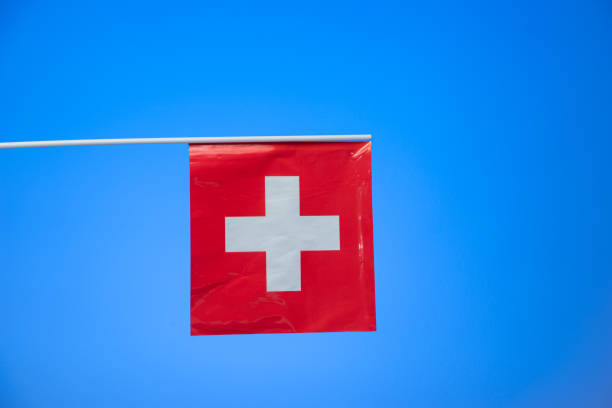 istock Small Swiss national flag isolated on blue background studio shot 1302622406