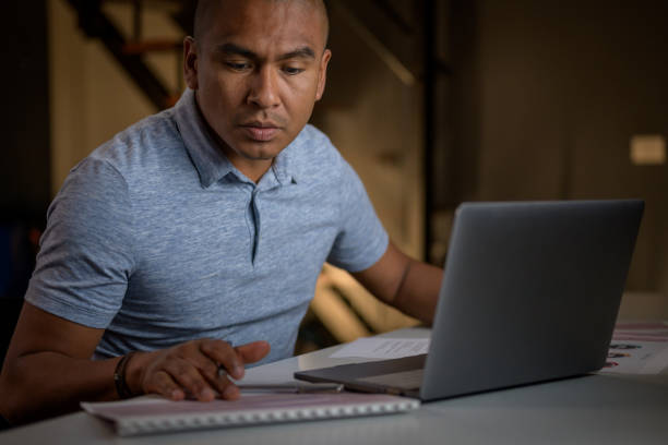 istock Adult Hispanic man sitting at desk and learning in evening 1302623664