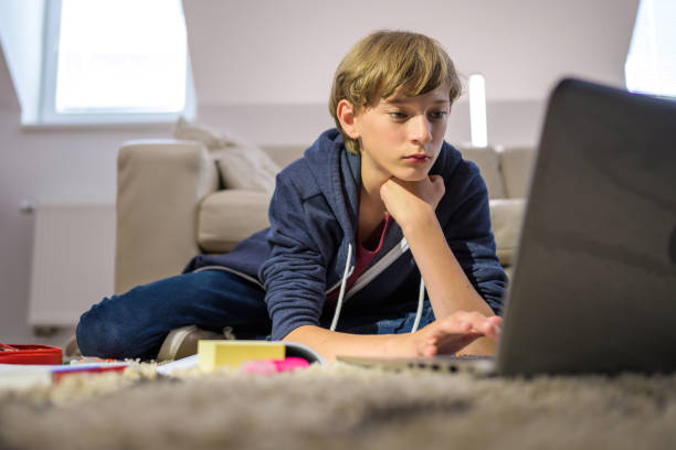 istock Teenage student sitting on carpet and working on laptop 1302623724