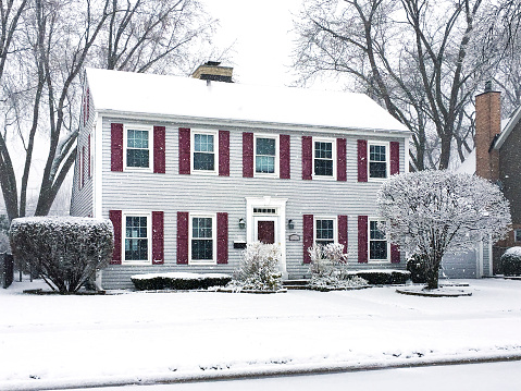 Snow falling on a saltbox colonial house
