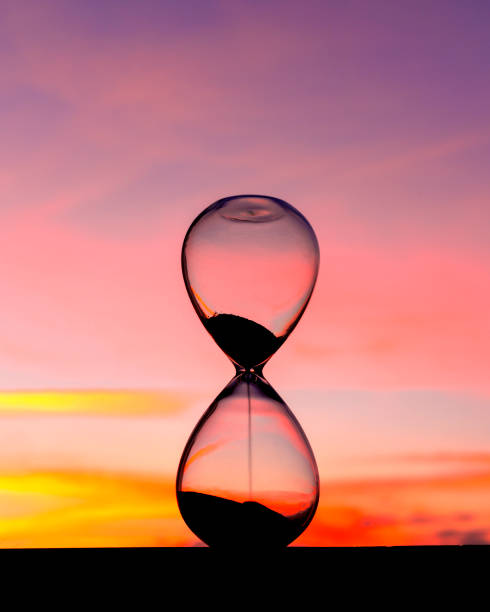 istock Time passing at sunset with hourglass 1302626248