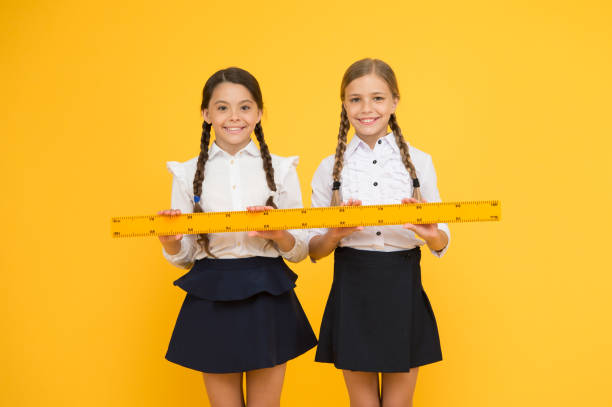 Measuring distance. Measuring equipment. Kids students study math. Knowledge day. Schoolgirls school uniform hold big ruler. Geometry school lesson. Teamwork concept. Close or far. Measuring skills