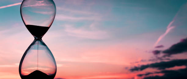 istock Time passing at sunset with hourglass 1302627002