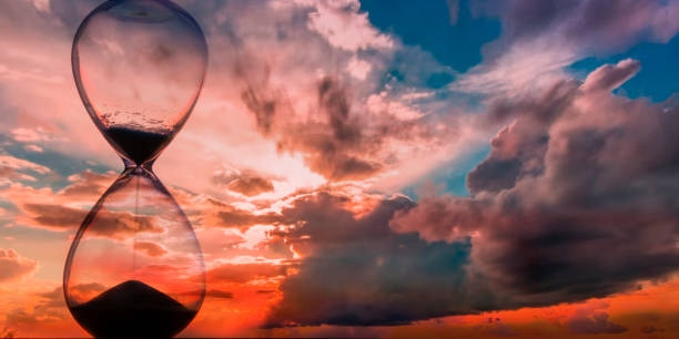 istock Time passing at sunset with hourglass 1302627193