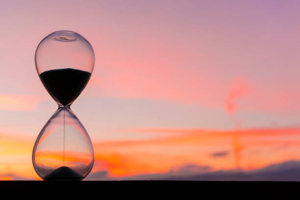 istock Time passing at sunset with hourglass 1302627196