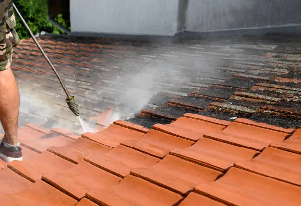 Photo of Rooftop washing. Clean roof tiles vs. dirt and lichen.