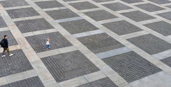 Man and little caucasian child walking at the street as pedestrian, at pavement from grey bricks, view from the top, urban life, outdoor, copy space.