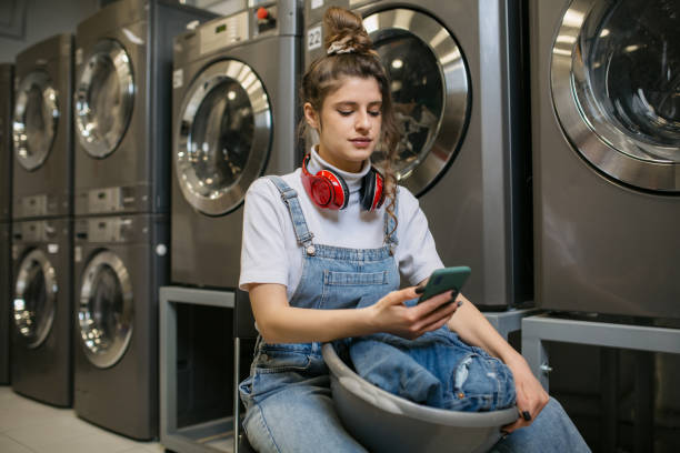 istock Young Caucasian woman doing laundry at the laundromat 1302634320