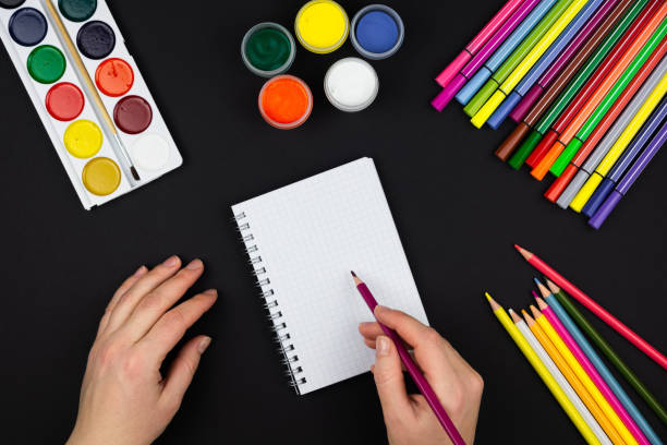 istock the girl makes a note in a notebook, next to pencils and paints 1302634684
