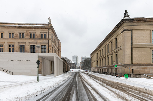 Berlin, Germany - February 9, 2021: view on empty street between the James Simon Gallery and Old Museum in berlin  under gray winter sky