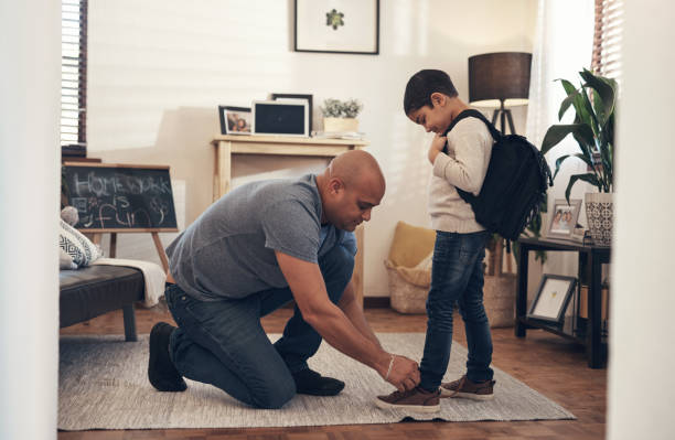 School is the first step on the stairway to success Shot of an adorable little boy getting his shoelaces tied by his father before leaving to go to school leanincollection stock pictures, royalty-free photos & images