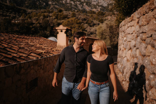 hermosa y sonriente pareja paseando por el rústico pueblo mallorquín de fornalutx - fornalutx majorca spain village fotografías e imágenes de stock