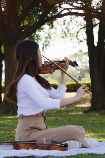 istock Young beautiful lady playing violin in a park.relax time , 1302641069