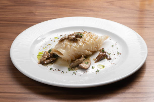 istock Fried squid with mushrooms and herbs on a white plate 1302645645