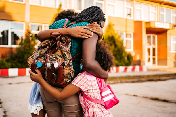 istock Happy daughters embracing their mother after classes 1302646447