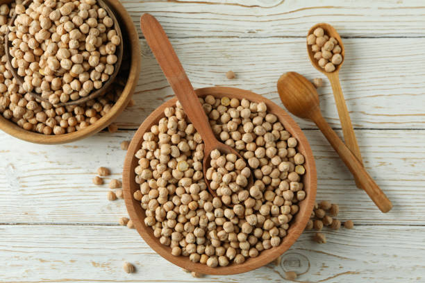istock Bowls and spoons with chickpea on white wooden table 1302647002