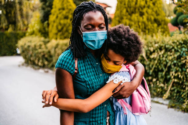 istock Mother embracing daughter in front of school 1302647277