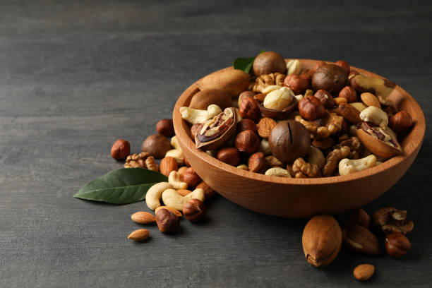 istock Wood bowl with different tasty nuts on gray wooden background 1302648043