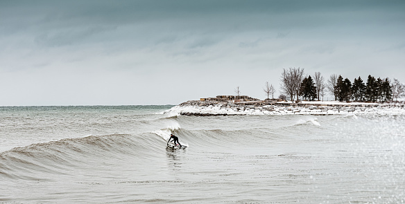 Canadian style surfing: Mature man  surfing the waves at the lake. Surfing in extreme weather conditions.