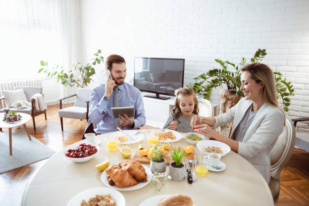 istock Busy family eating breakfast at a dining table at home 1302651018