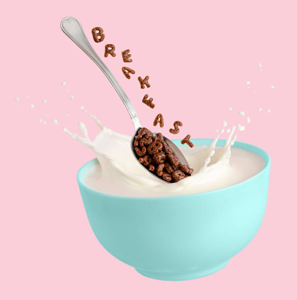 istock Cocoa cereal letters falling into blue bowl with splashing milk. Breakfast for children. Isolated on pink background. 1302651923