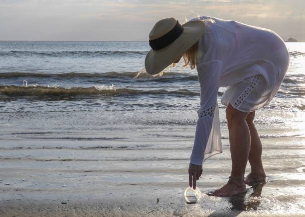istock Woman picks up garbage on beach in the morning 1302652094