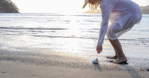 istock Woman picks up protective face mask littered on beach 1302652095
