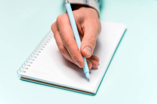 istock A man's hand writes in a notebook, minimalism on a blue background, space for text 1302652309