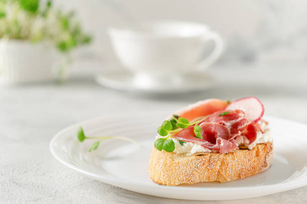 Mediterranean appetizer. Open sandwich with prosciutto or jamon on white plate. Copy space Mediterranean appetizer. Open sandwich with prosciutto on white plate. Breakfast concept spanish breakfast stock pictures, royalty-free photos & images