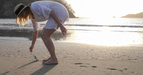 istock Woman picks up protective face mask littered on beach 1302652727