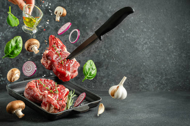 istock Raw veal bone steak falling on the grill pan with ingredients for cooking on dark background. Copy space. 1302652938