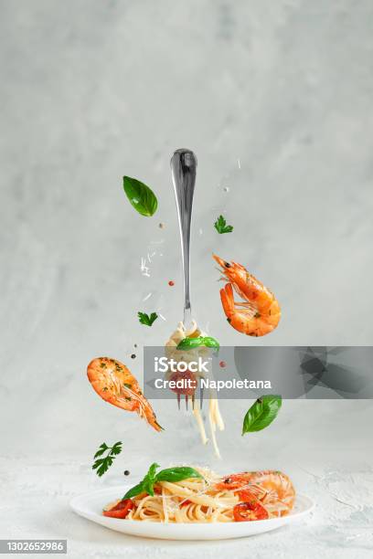 Pasta Linguine With Prawns And Fork Flying Over The Dish Creative Still Life Italian Food Stock Photo - Download Image Now