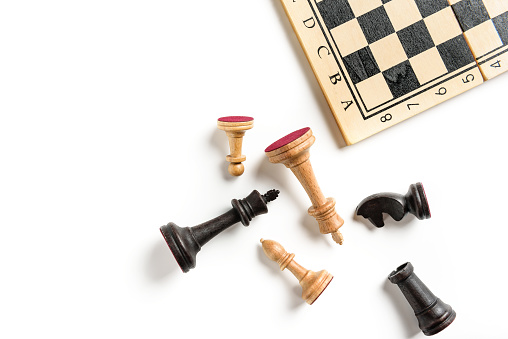 Flat lay composition with chess pieces and chessboard isolated on white background with copy space.