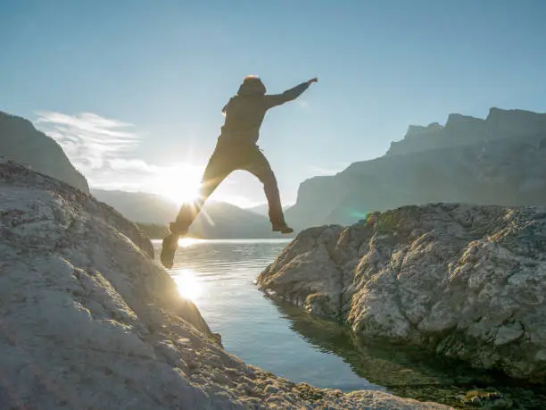 Photo of Young man jumps across gap over mountain lake