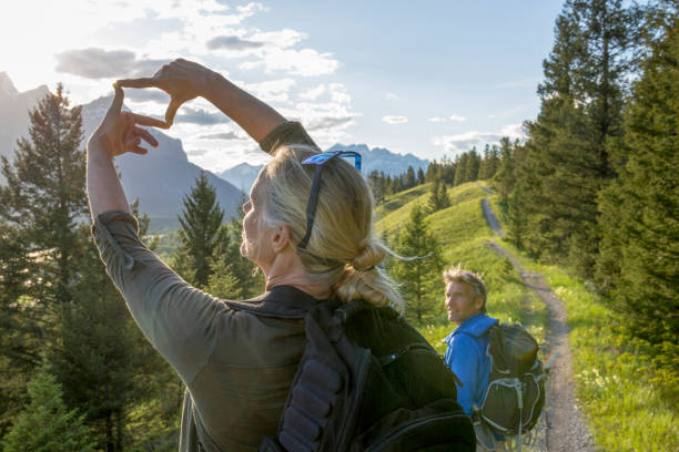ハイキングは、パートナーの時計として山の上にフレームを作ります - 指のフレーム ストックフォトと画像