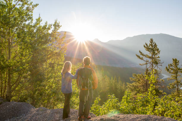 Hiking couple watch the sunset over mountains