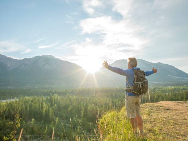 istock Hiker stretches arms out on mountain bluff, sunrise 1302654728